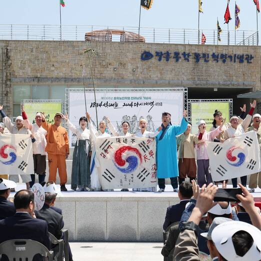 장흥동락농민혁명 기념관 앞에서 퍼포먼스 중인 관계자들과 앉아서 관람중인 관객들(크게보기)